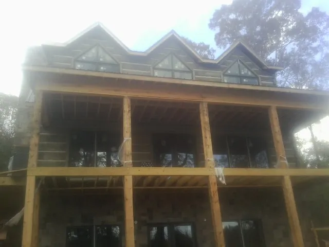 Dormers and porch framing on a large log home under construction — Roof Coating work by our crew in West Des Moines