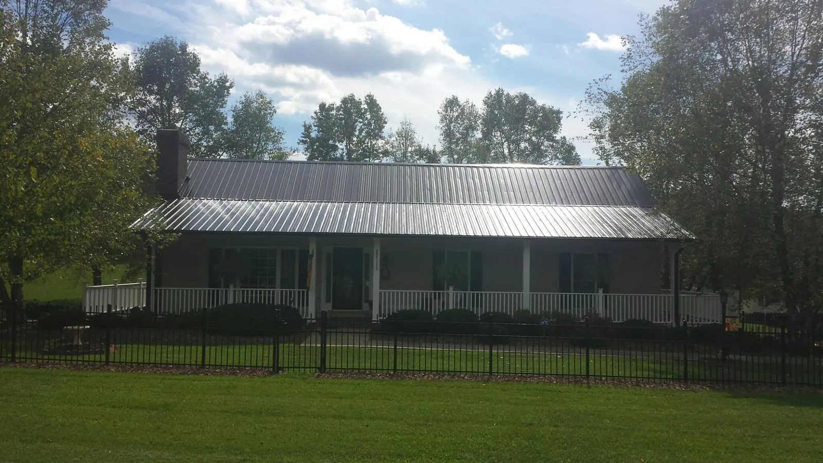 Gray metal roof on a brick ranch with a full width front porch — Gutter Guard Installation work by our crew in West Des Moines