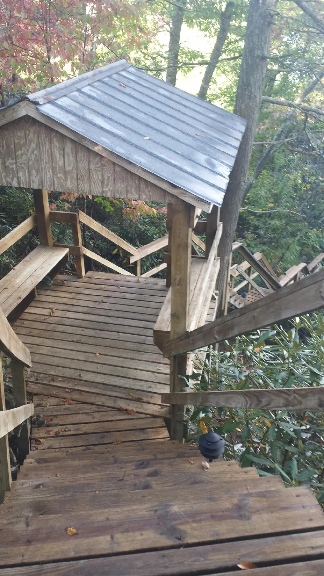Metal roofed shelter over wooden steps on a wooded walkway — Skylight Repair & Installation work by our crew in West Des Moines