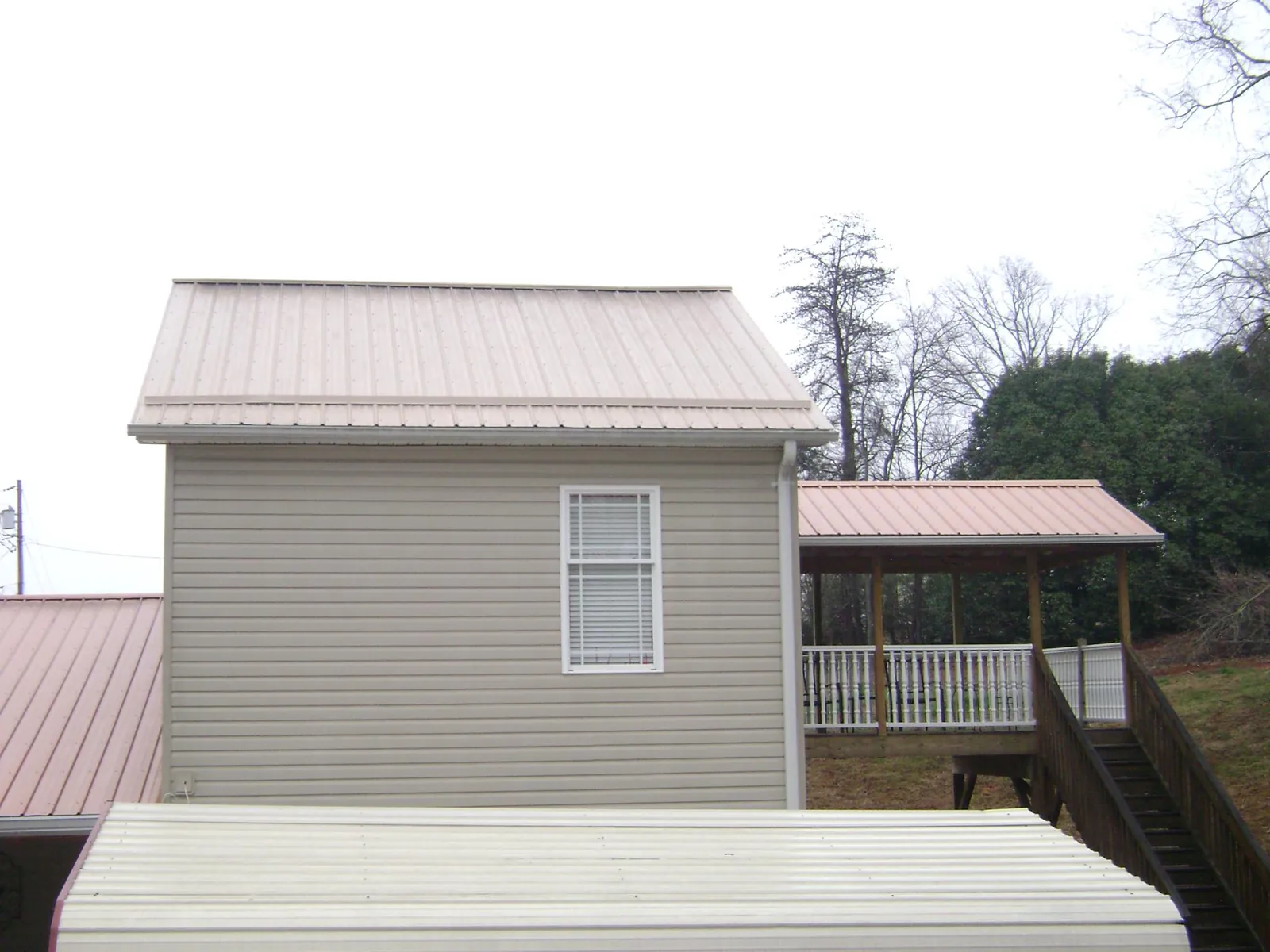 Tan metal roofs on a two story addition and attached porch, from a Roof Replacement job in West Des Moines
